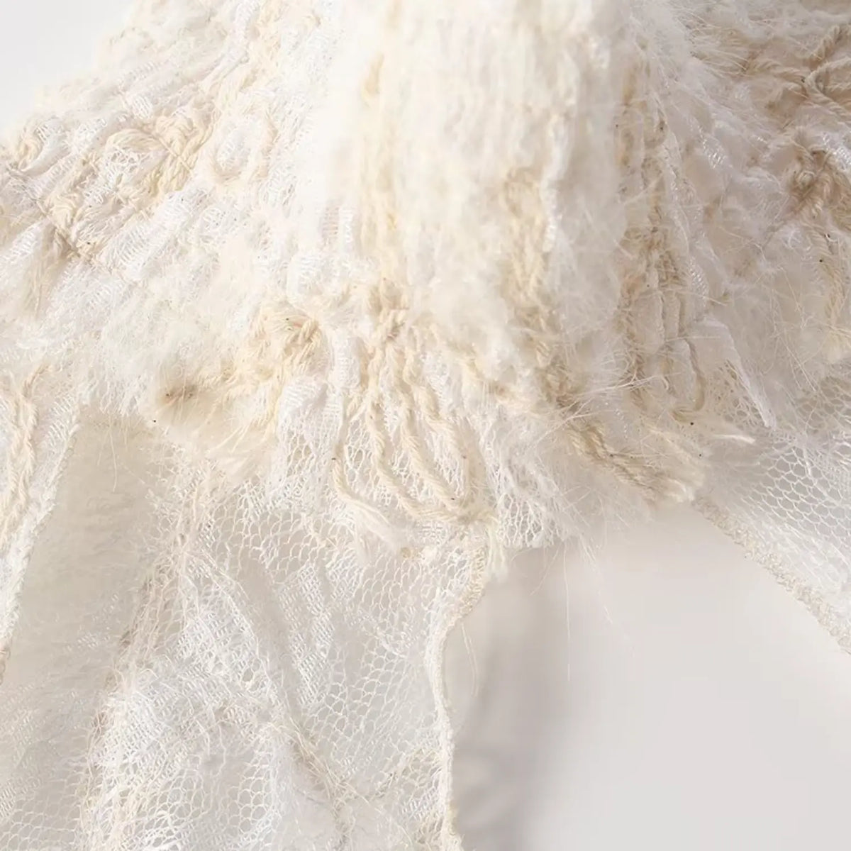 Detailed shot of smocked high neck, gathered ruffle and lace embroidery texture of cream lace top