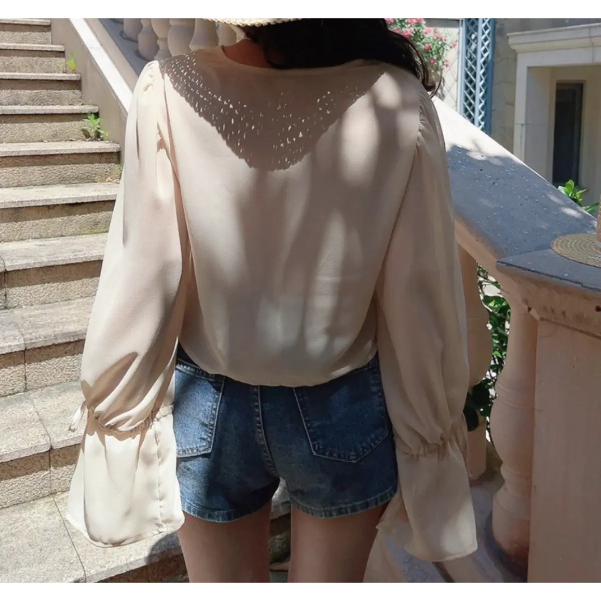 Back view of a model wearing a cream lace-trim chiffon blouse, showing the flowy silhouette and gathered sleeves.