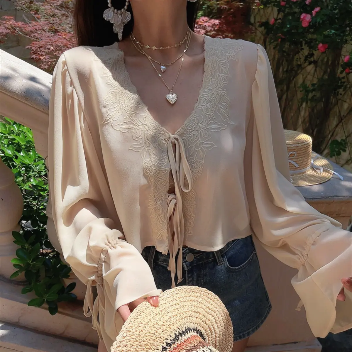 Close-up shot of a model wearing a cream lace-trim chiffon blouse, highlighting the V-neck and lace embroidery.