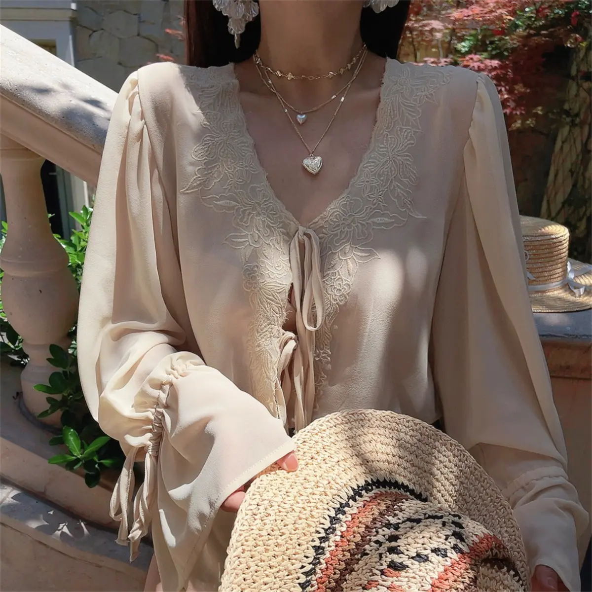 Detail view of a cream lace-trim chiffon blouse, showing the front tie closure and lace detailing.