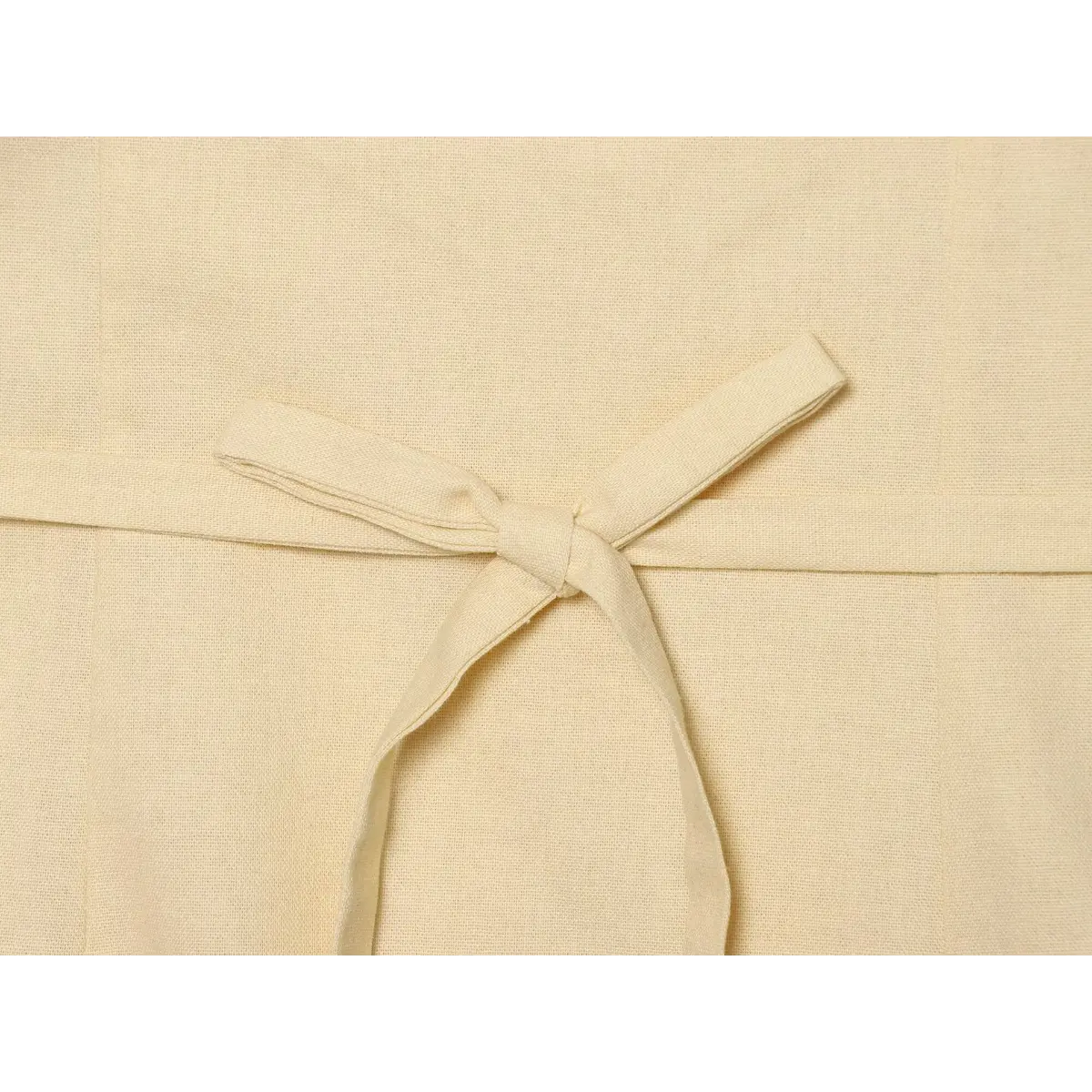 Close-up of the fabric tie closure at the back waist of a cream-colored top.