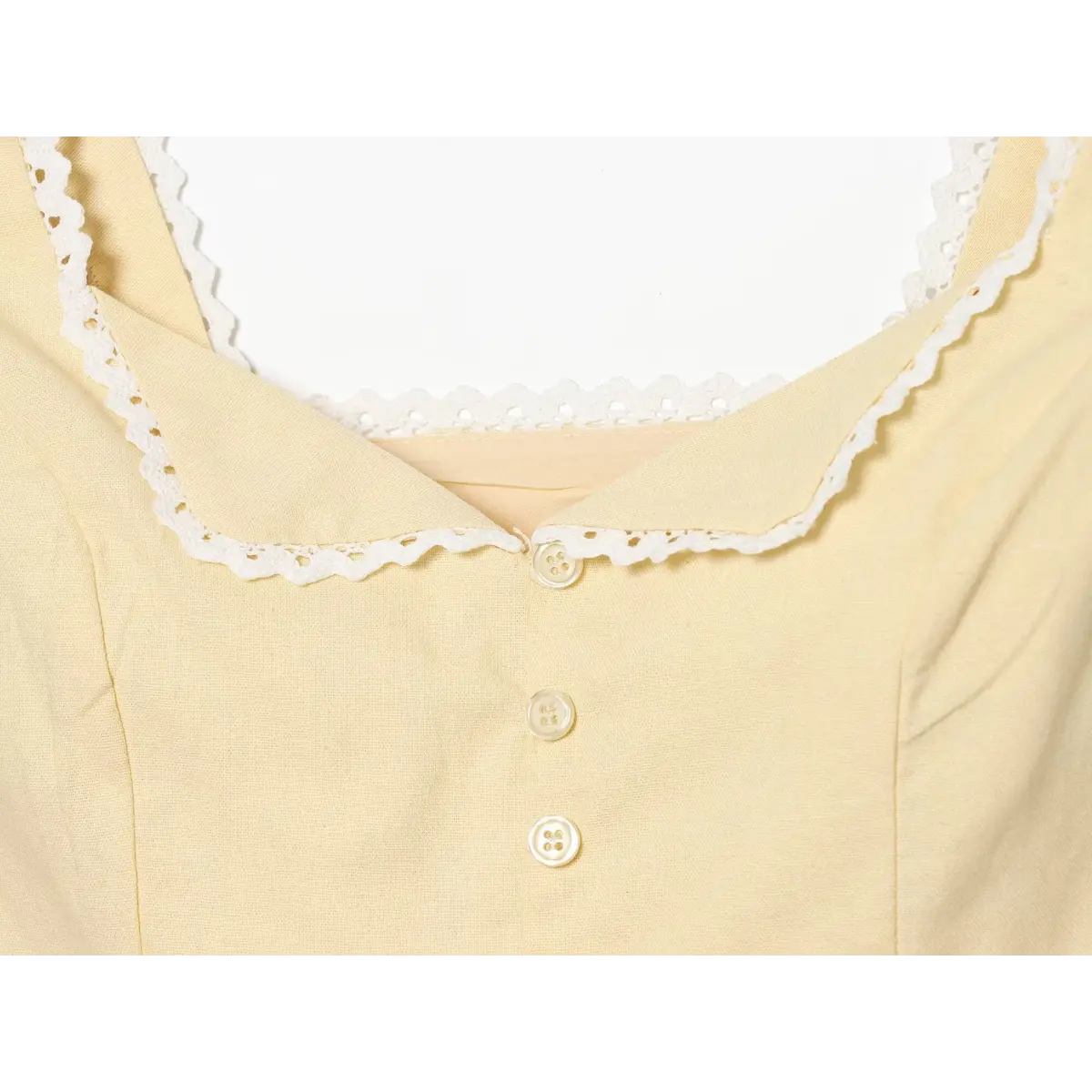 Close-up of the front button placket and lace-trimmed neckline on a cream-colored top.