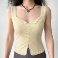 Full-body shot of a woman wearing a cream-colored lace-trimmed corset-style top with gray bottoms.