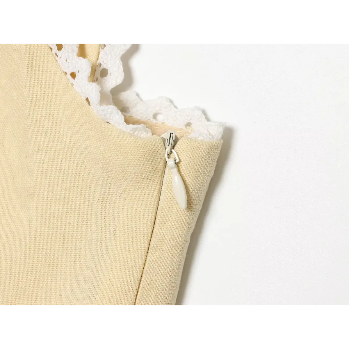 Close-up of the side zipper on a cream-colored lace-trimmed top.