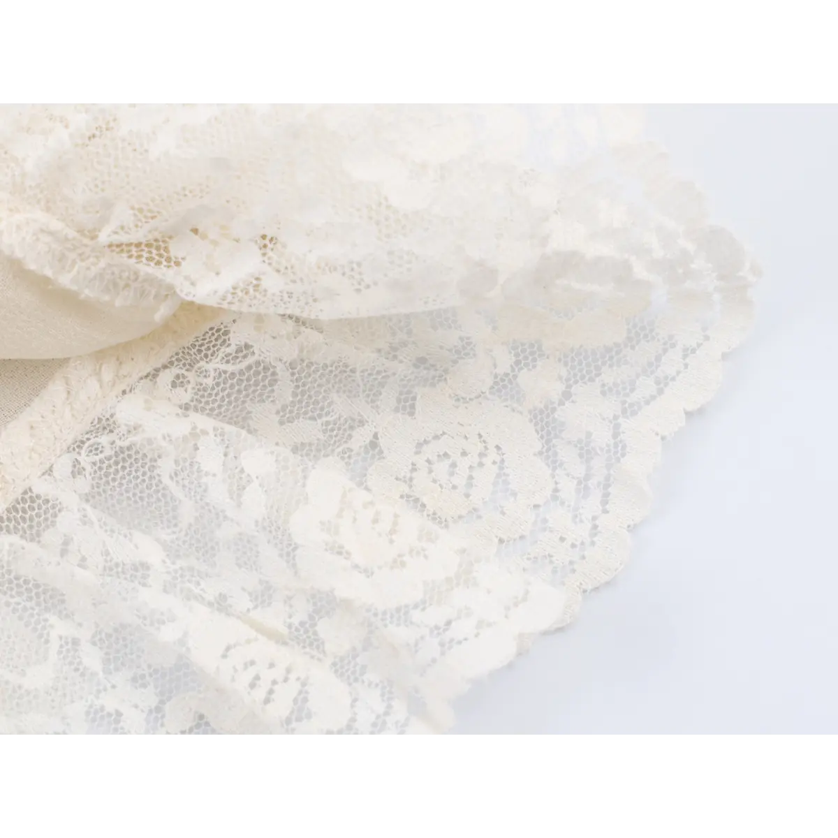 Close-up detail of the floral lace fabric on a cream camisole, highlighting the rose pattern and delicate texture.