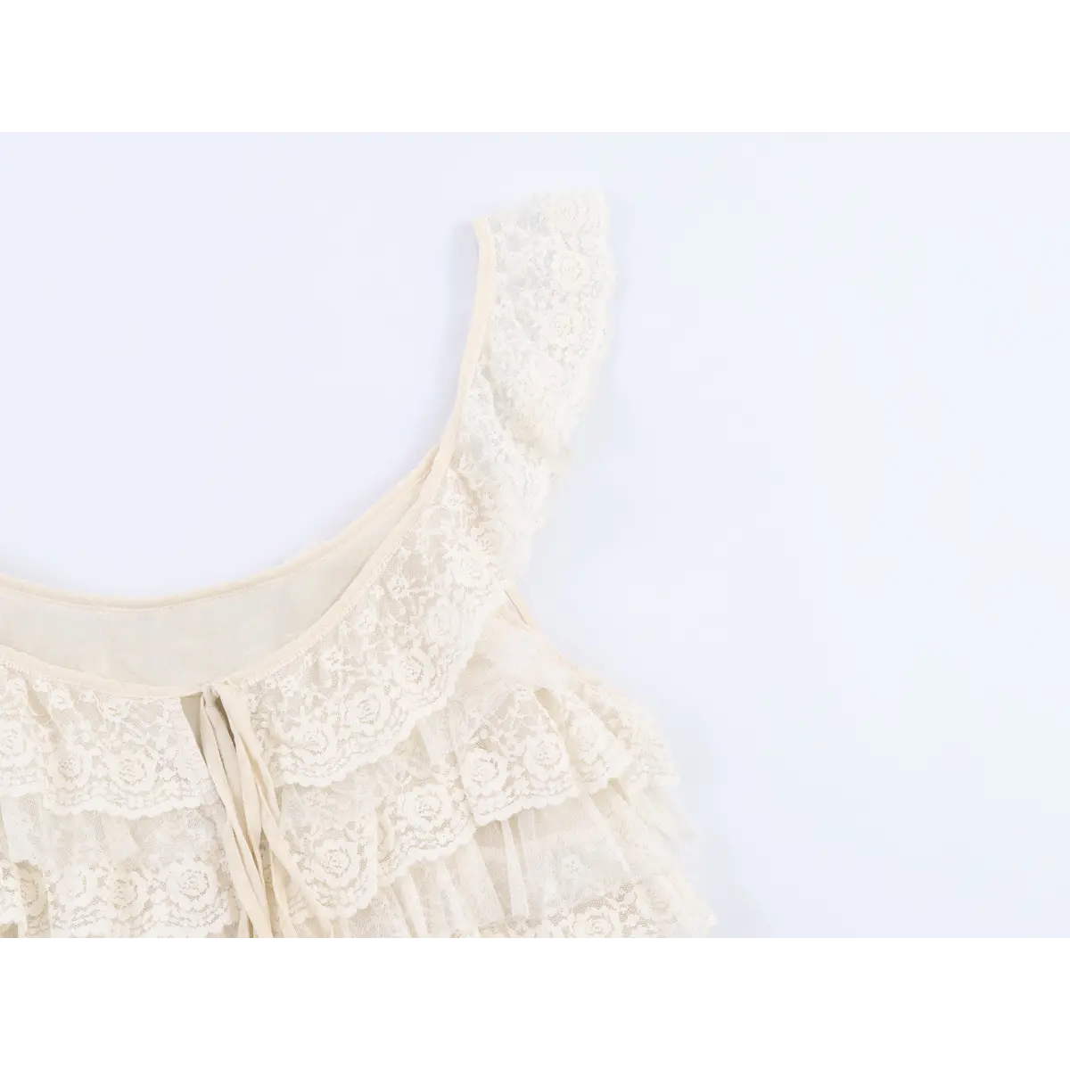 Close-up view of the lace strap and ruffled neckline of a cream layered lace camisole, highlighting the intricate floral lace pattern.
