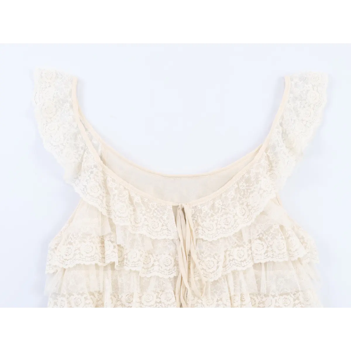Close-up view of the bust area of a cream layered lace ruffle camisole, showing the front tie detail and floral lace pattern.
