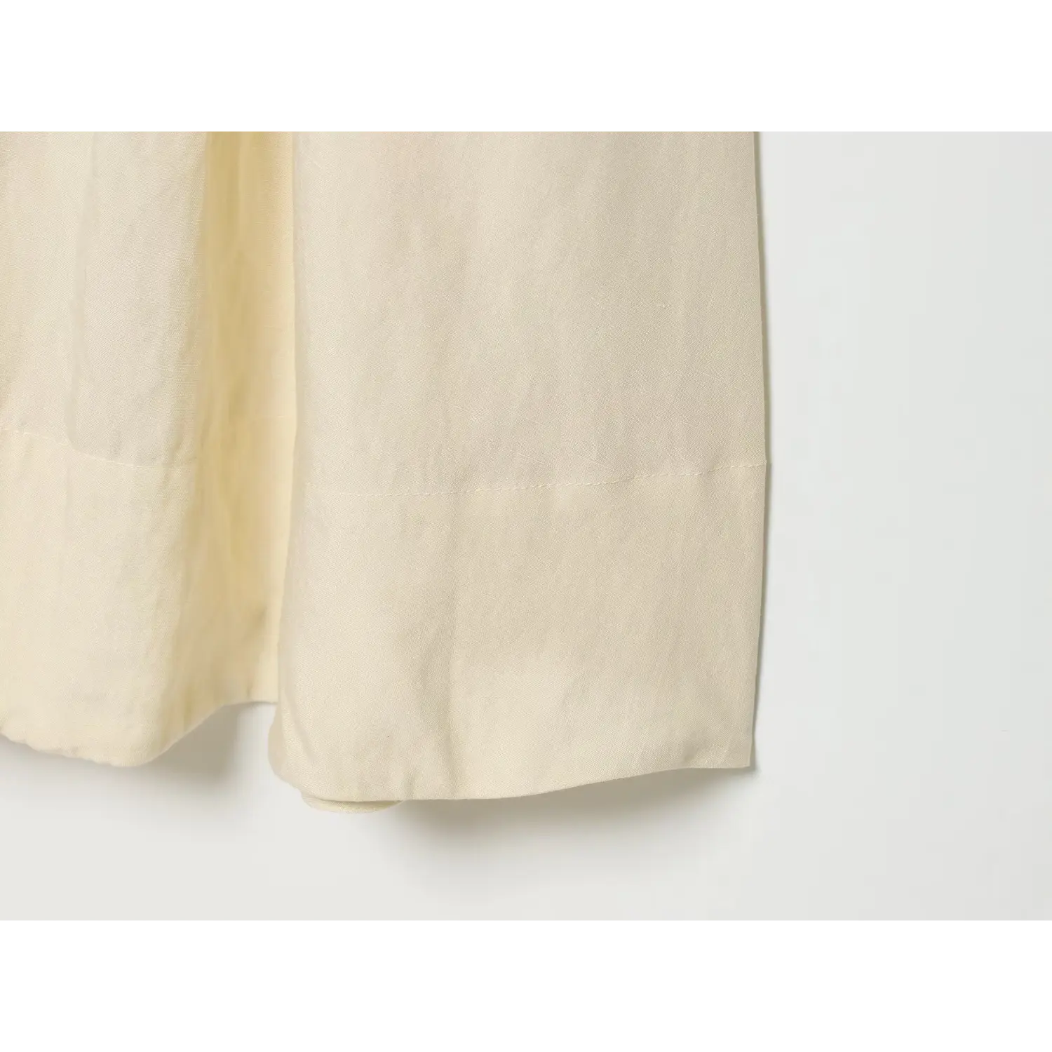 Close‑up of finished bottom hem stitching and textured linen blend fabric