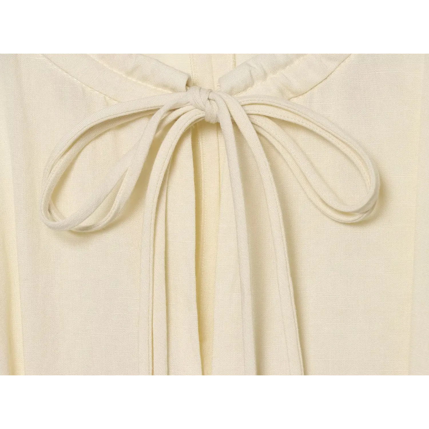 Macro close‑up of front neck self‑fabric tie knot on cream linen maxi dress