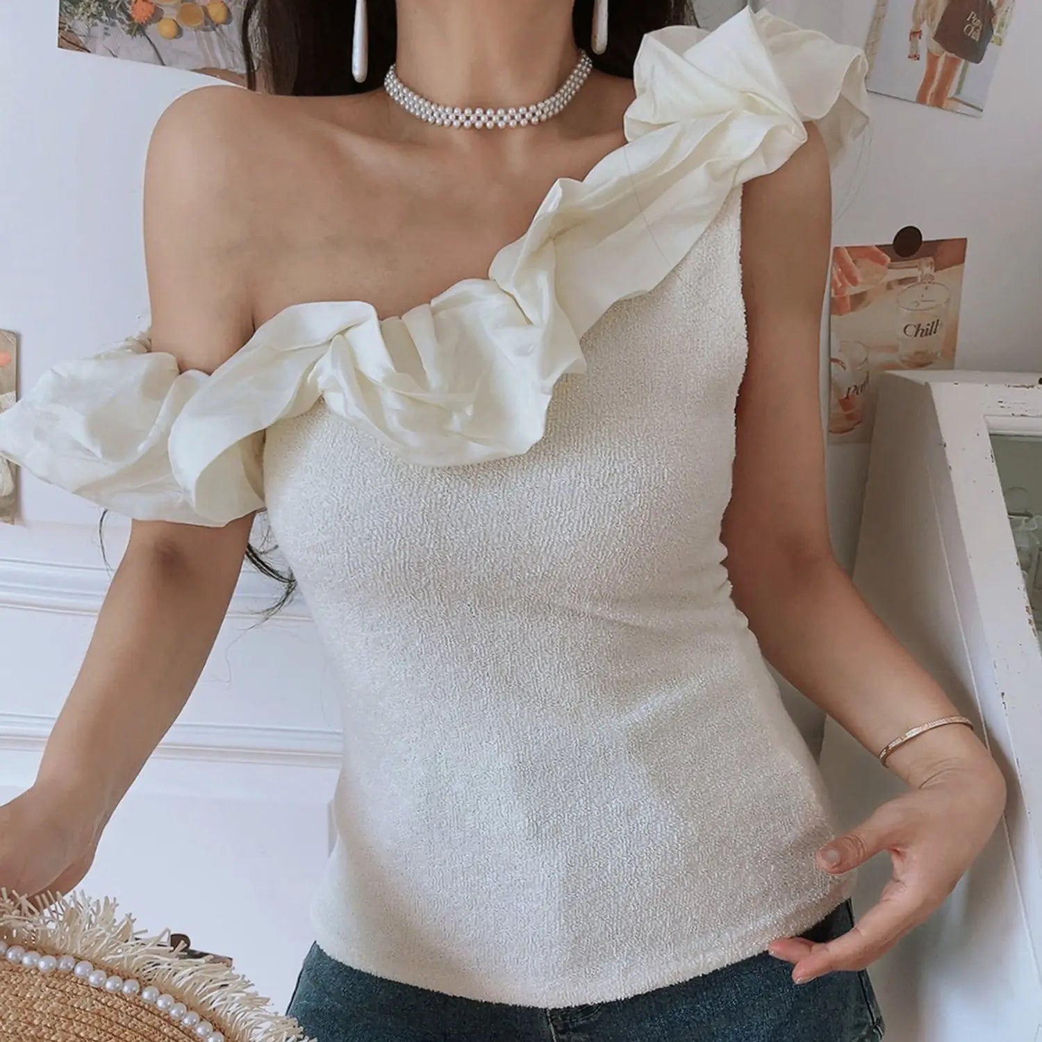Women cream textured knit one shoulder ruffle crop top, fitted silhouette, model with frayed pearl straw hat in front indoor shot