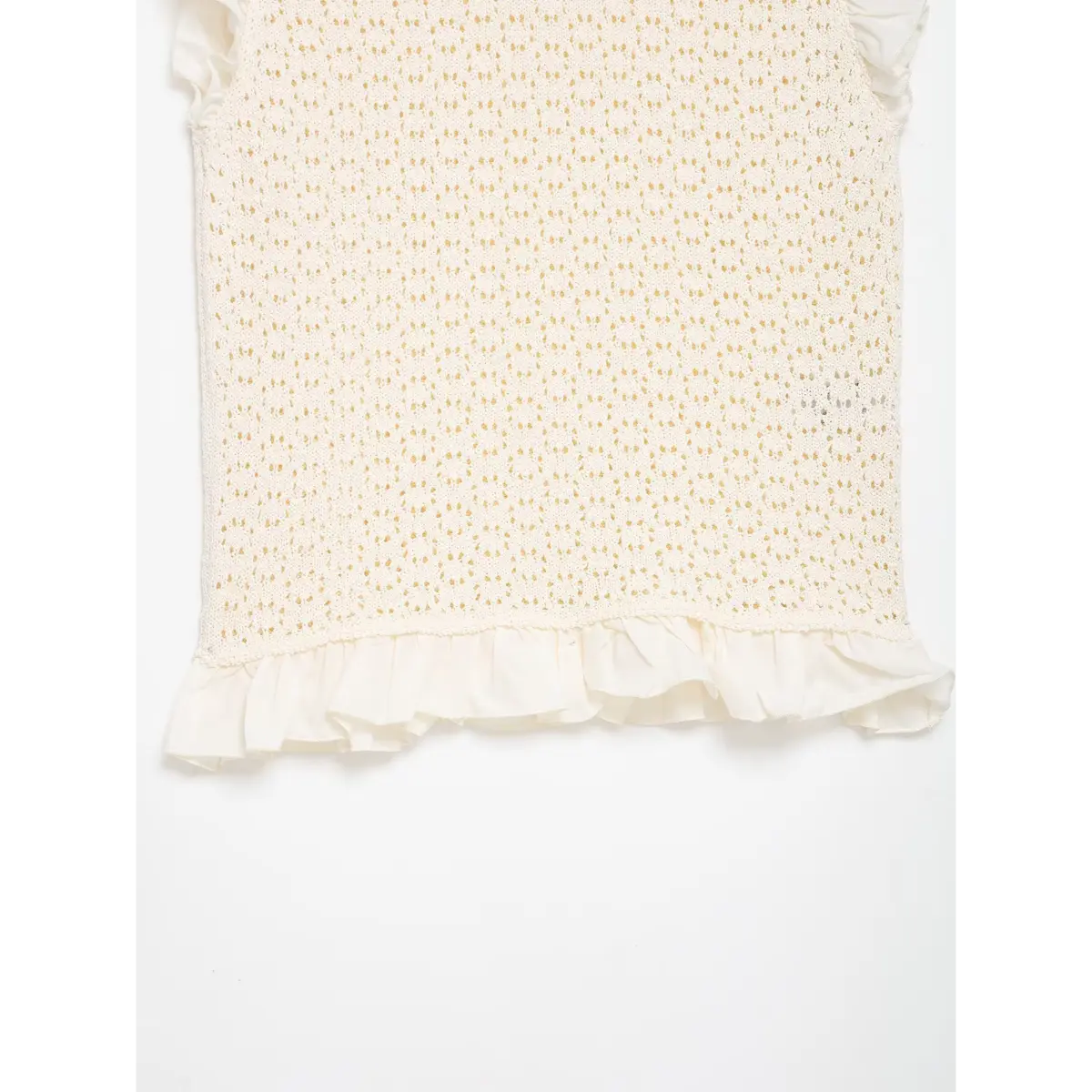 Back view of cream openwork knit top, showing the ruffled hem and lace-like texture