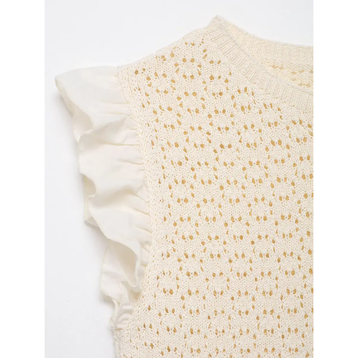 Close-up of the shoulder and ruffled sleeve on the cream openwork knit top