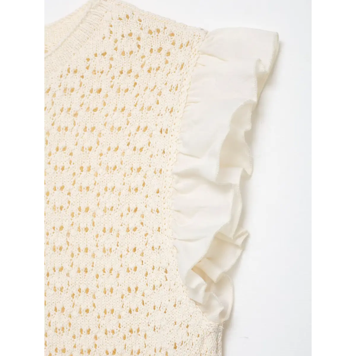 Close-up of the ruffled sleeve on the cream openwork knit top