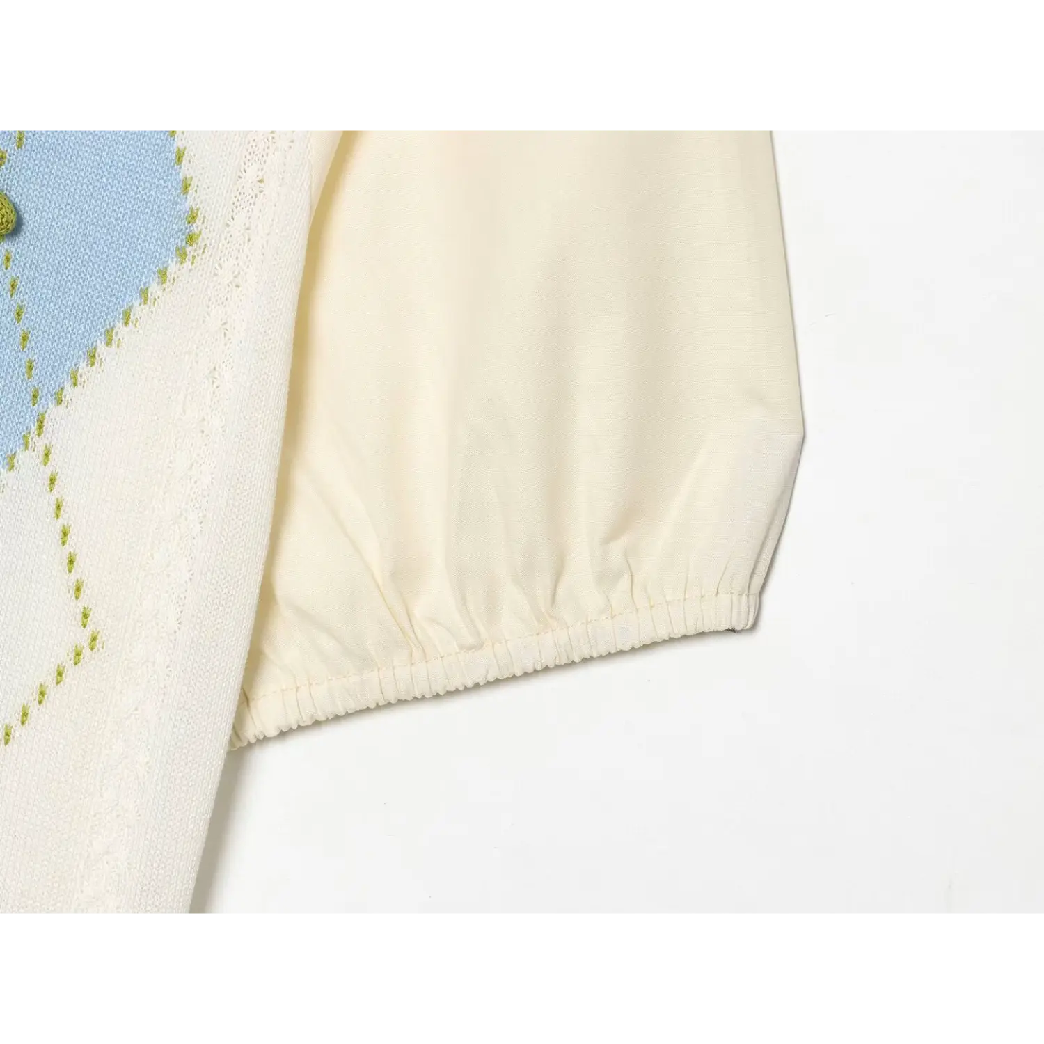 Side sleeve partial shot, smooth cream woven poplin bubble sleeve with elastic gathered cuff, spliced with argyle knit front bodice