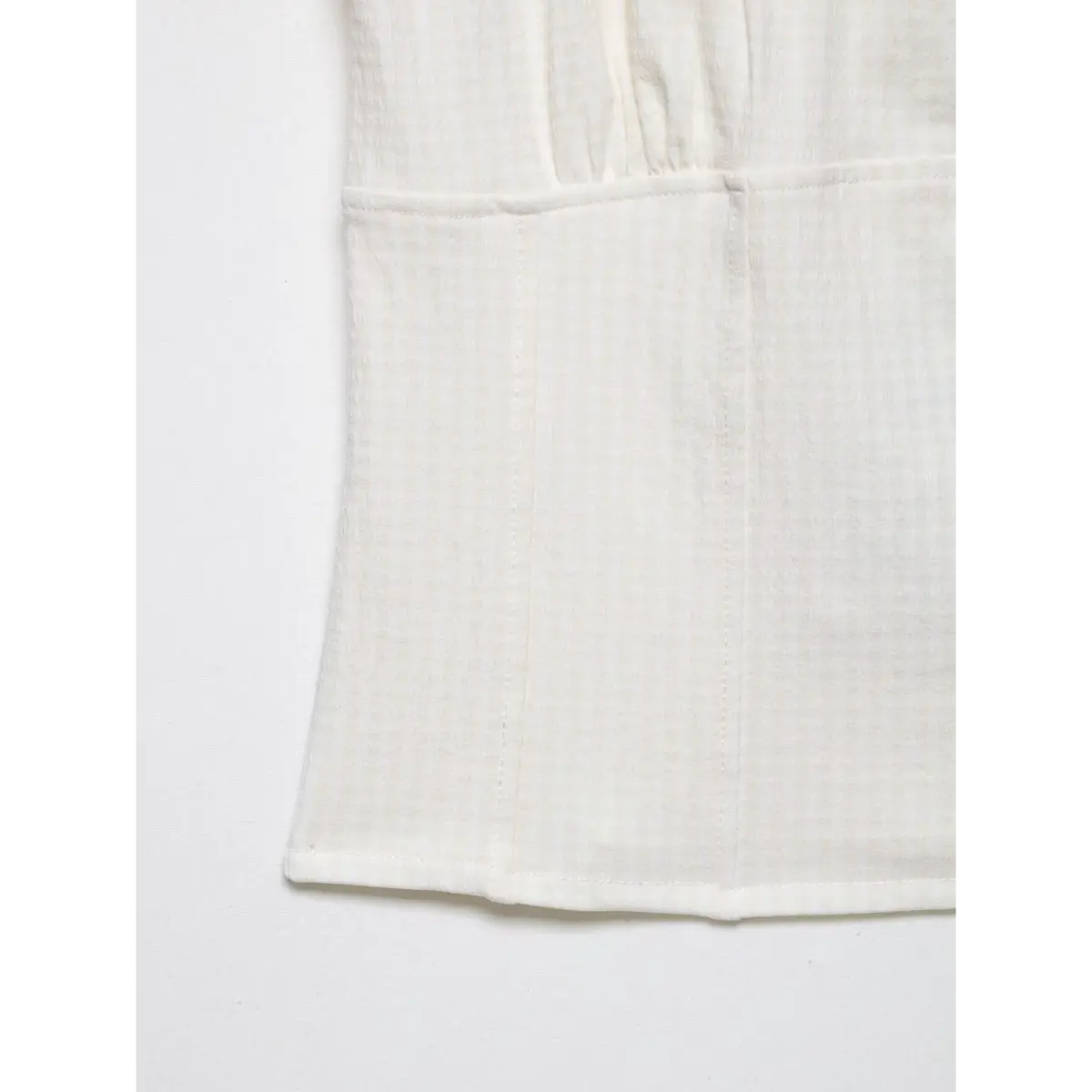 Close-up of the top's hem, showing the finished seam and gingham texture.