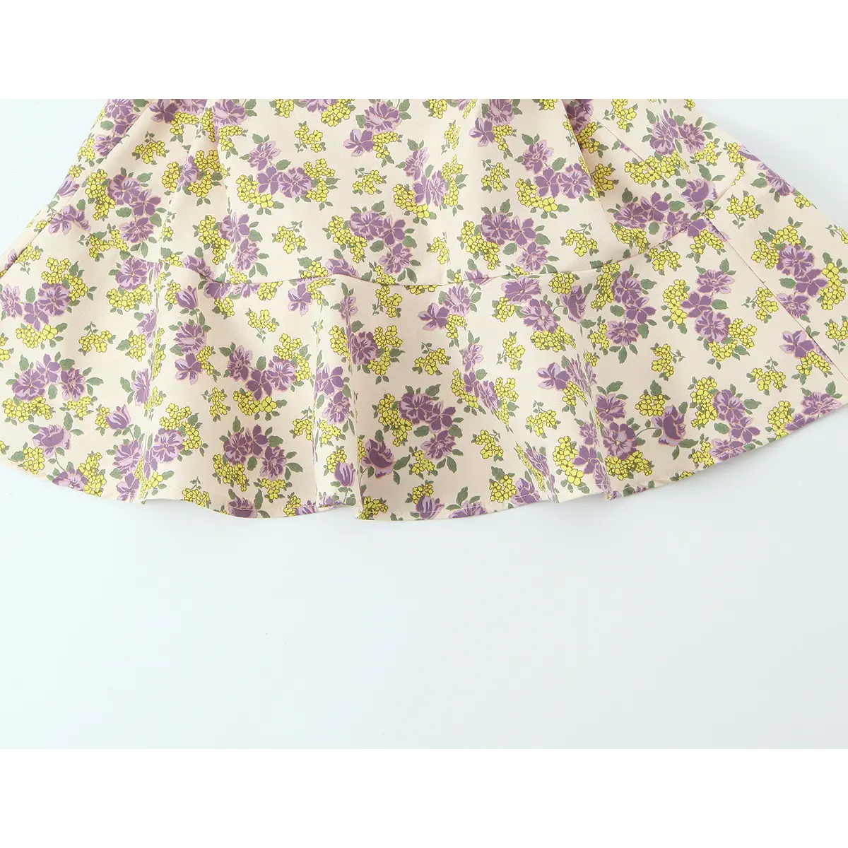 Hem view of the cream floral dress, showing the ruffled tiered skirt and floral print pattern