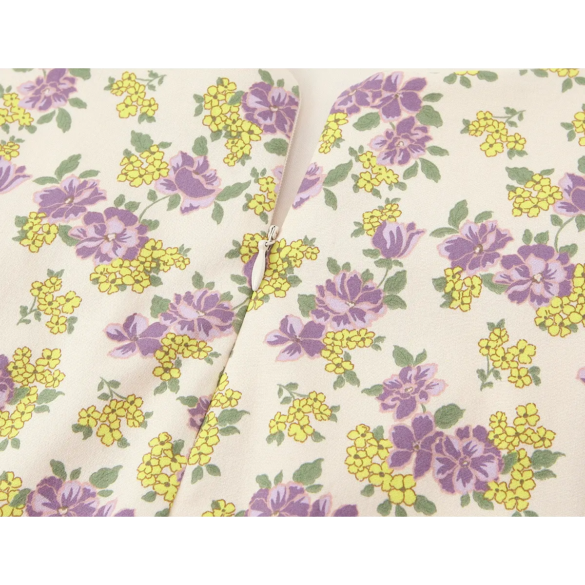  Close-up of the side zipper on the cream floral dress, showing the matching pull and purple/yellow floral print