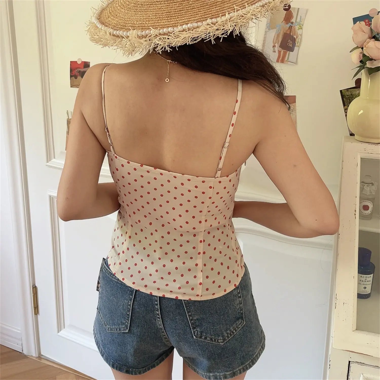 Lifestyle back shot of model wearing cream red polka dot cami top