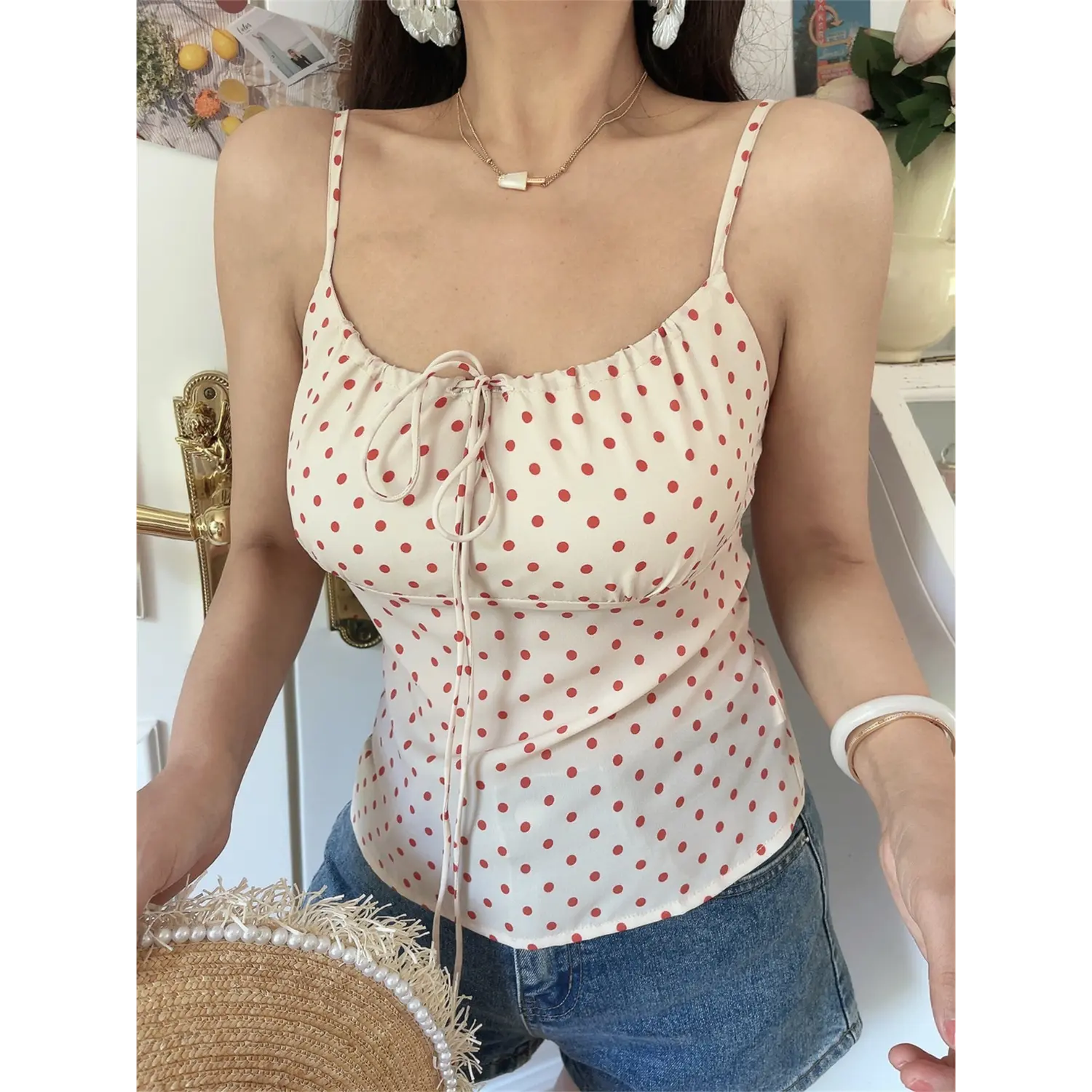 Close-up lifestyle shot of model wearing cream red polka dot cami with jeans