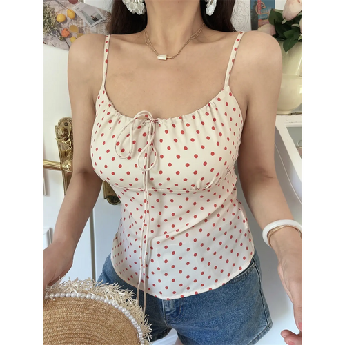 Close-up lifestyle shot of model wearing cream red polka dot cami with jeans