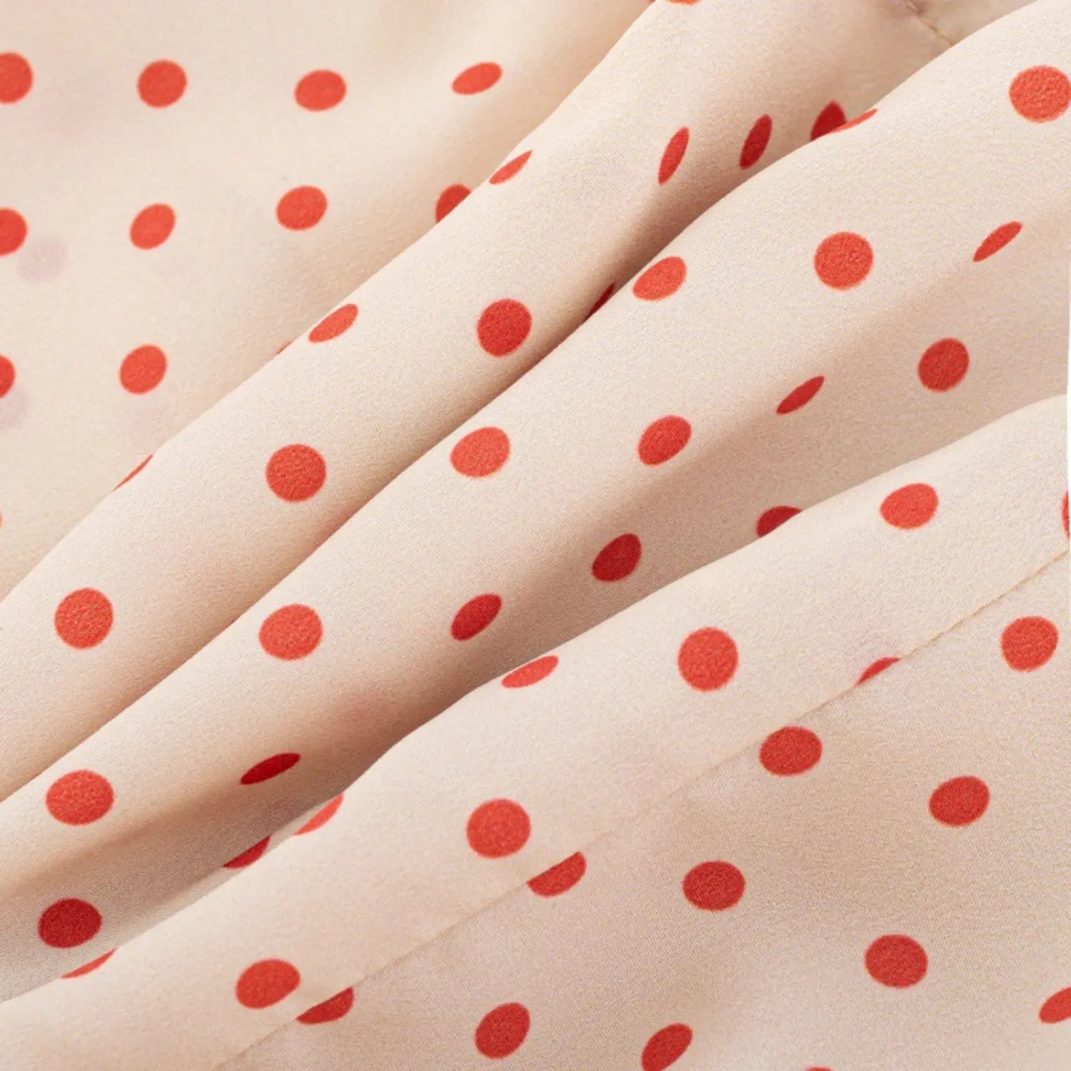 Close-up of lightweight chiffon fabric texture with red polka dot print