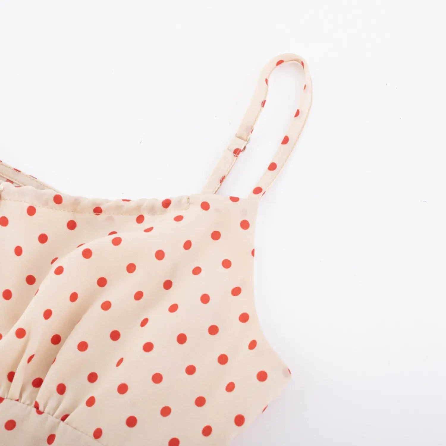 Close-up of adjustable spaghetti straps and neckline detail on cream red polka dot camisole
