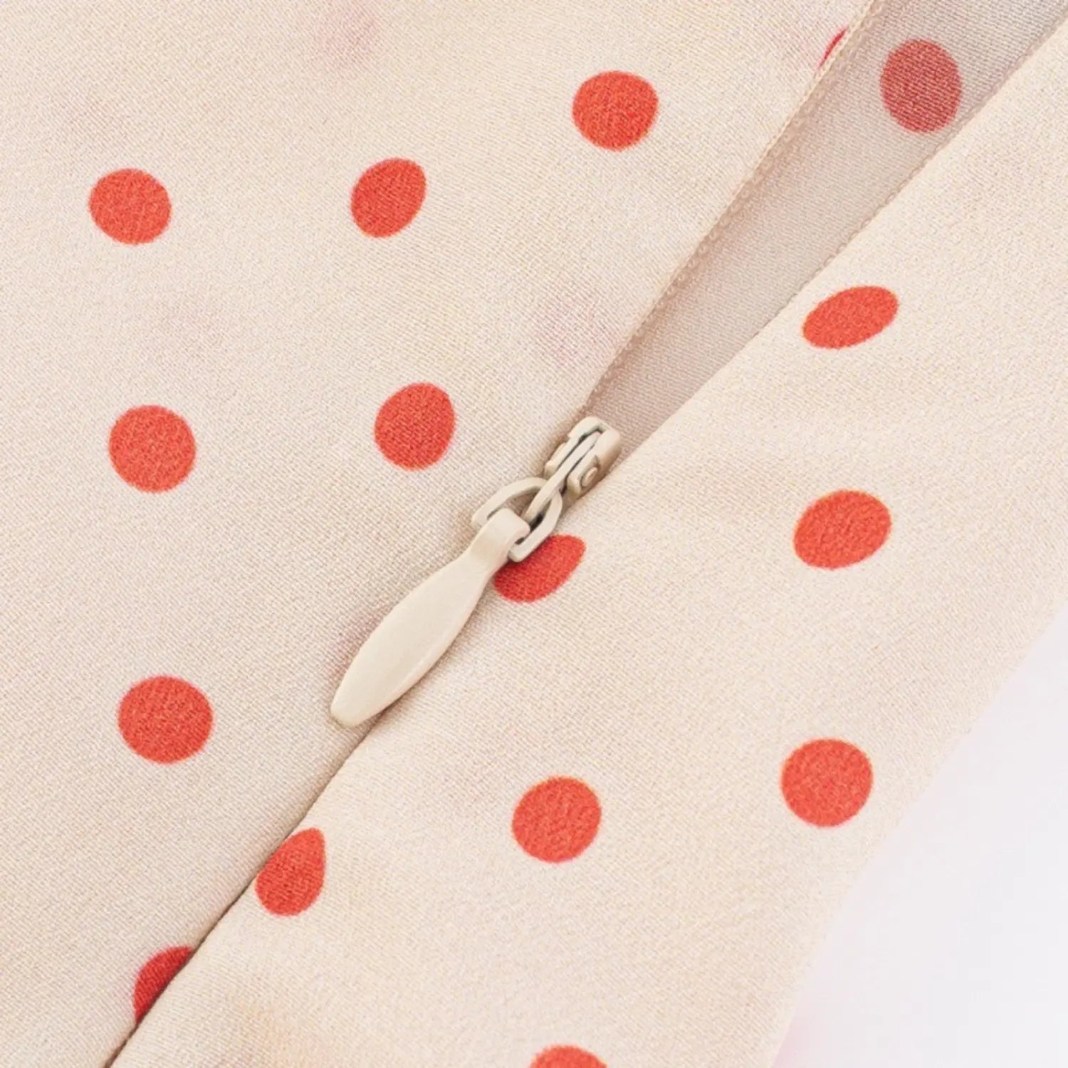Close-up of the side invisible zipper closure on cream red polka dot camisole