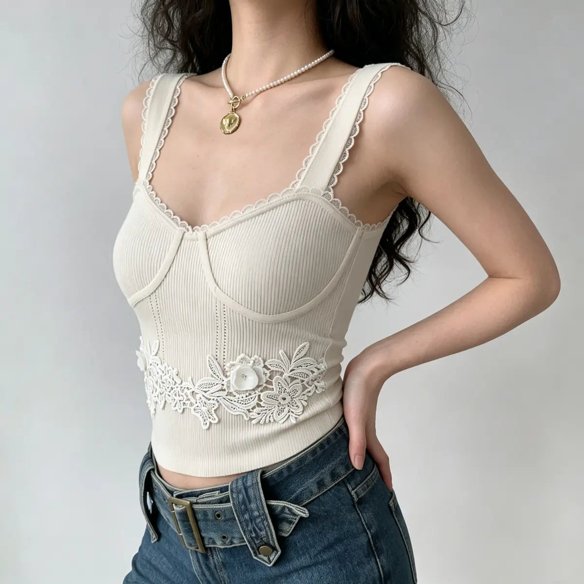 Side view of a model in a cream ribbed cami top, highlighting the bustier-style seams and floral lace appliqué.