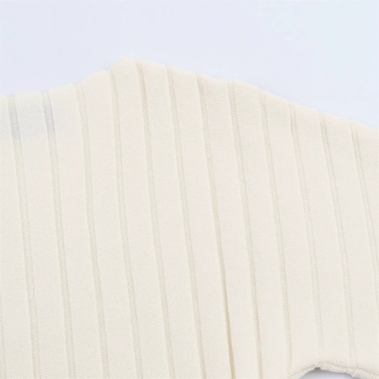 Texture shot of cream ribbed knit fabric, showing stitch detail and stretch texture