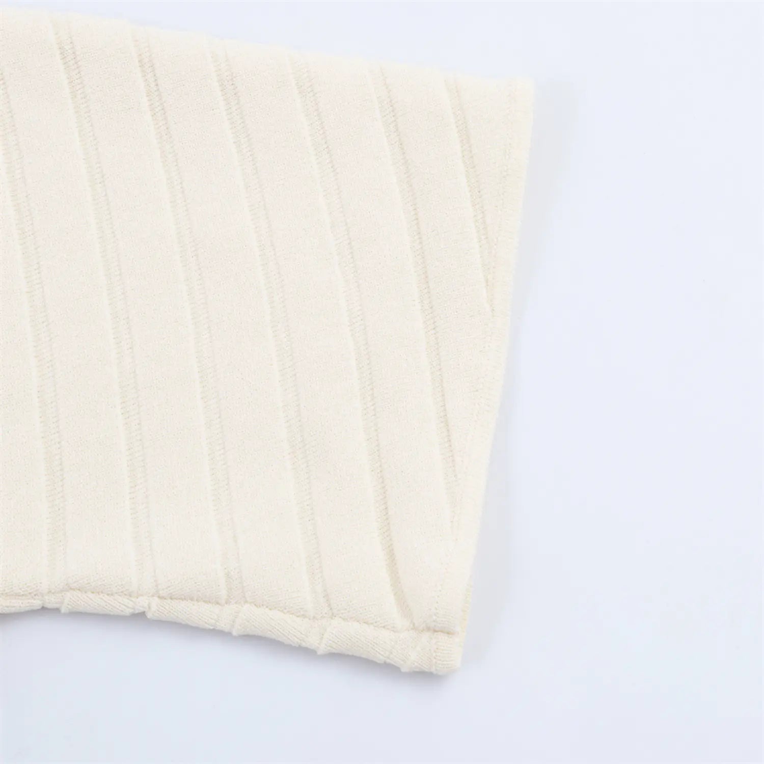 Hem and sleeve cuff detail close-up of cream ribbed knit mini dress