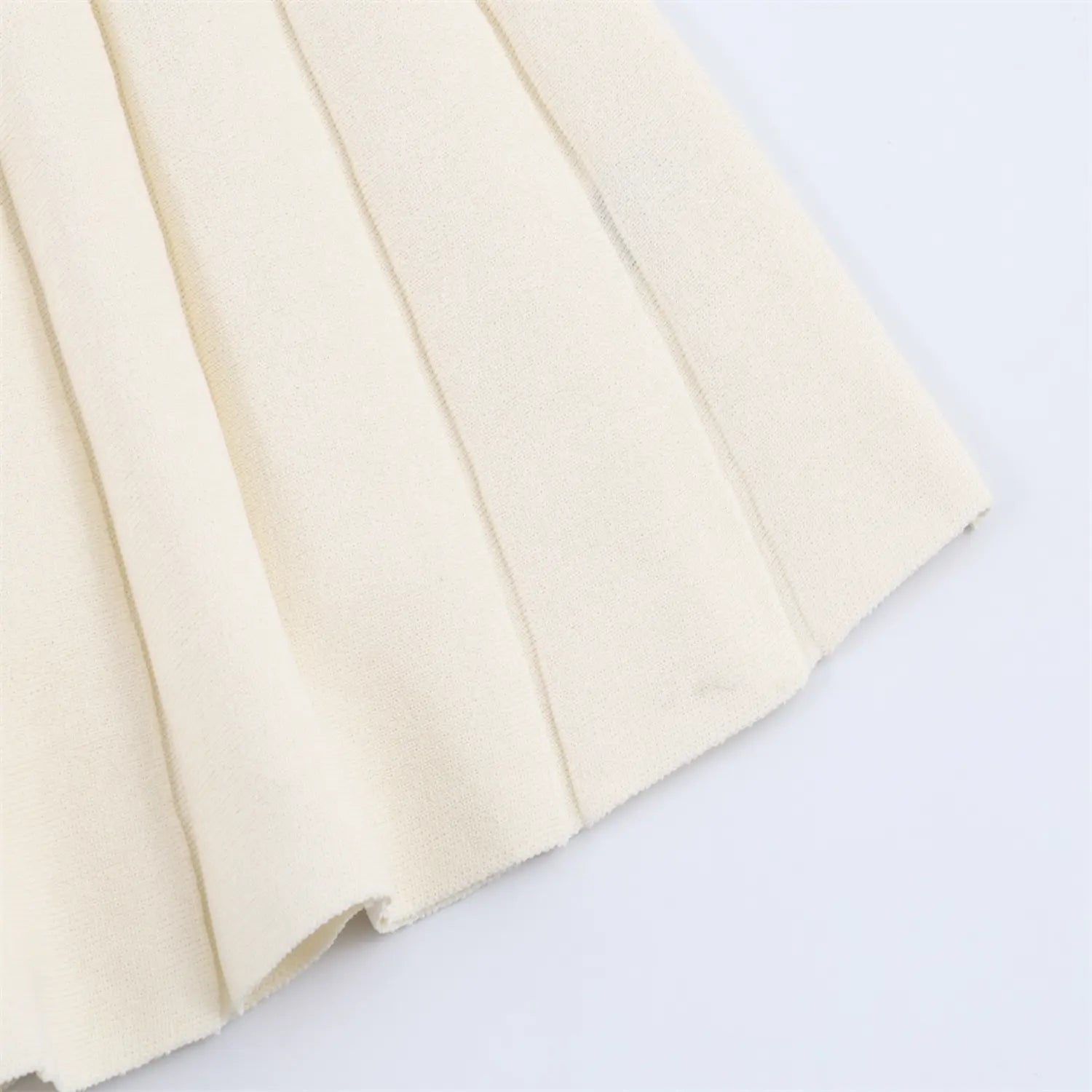 Hem stitching detail of cream ribbed knit dress, showing finished edge craftsmanship