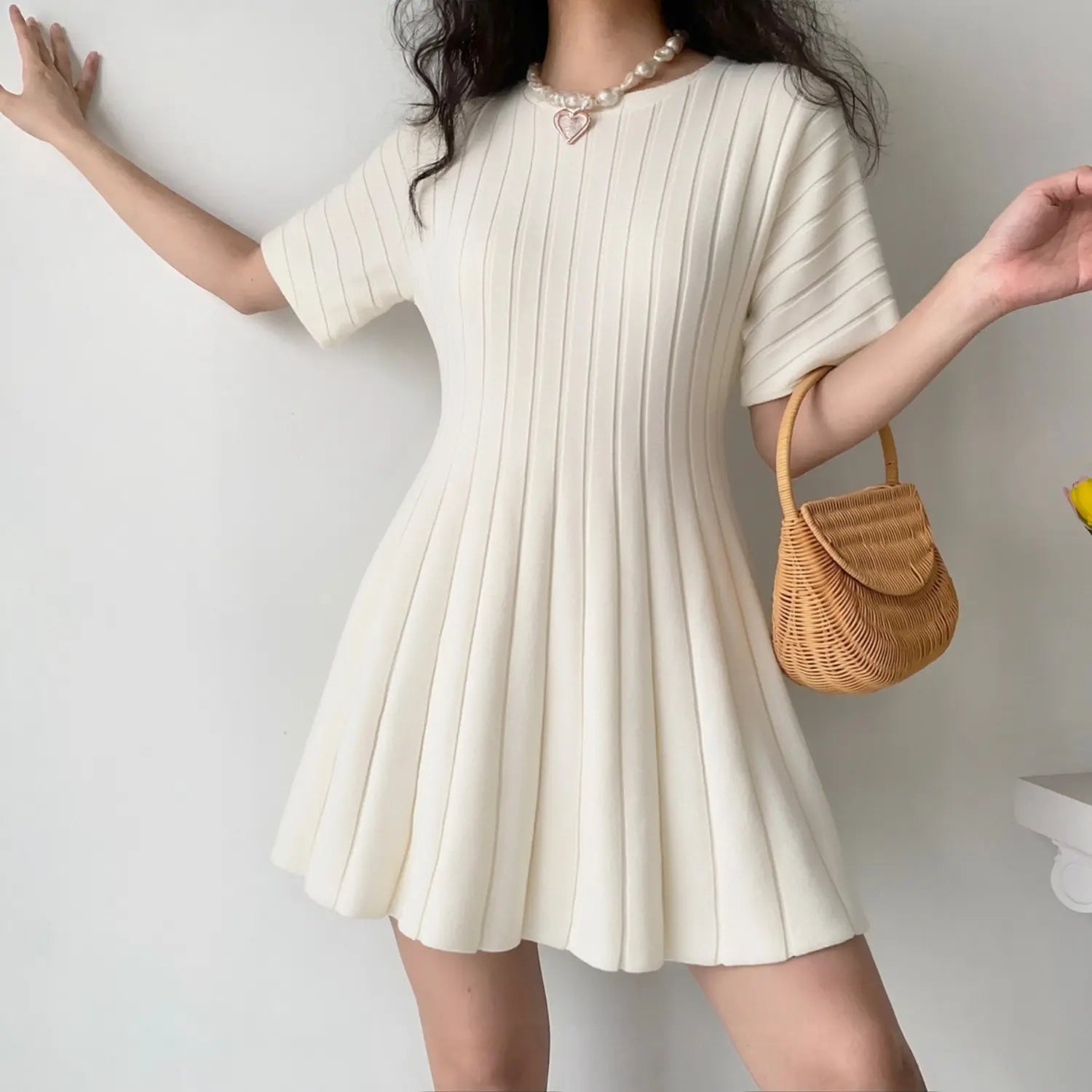Model front view wearing cream ribbed knit mini dress, round neck short sleeve A-line silhouette