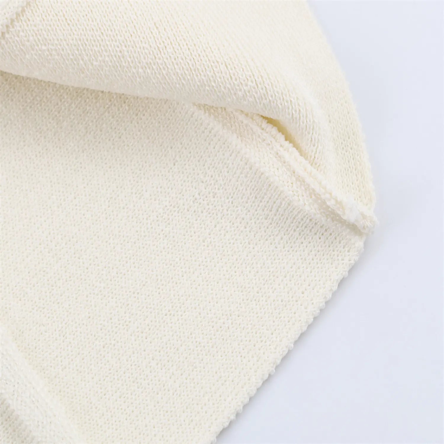Neckline and sleeve cuff detail close-up of cream ribbed knit mini dress
