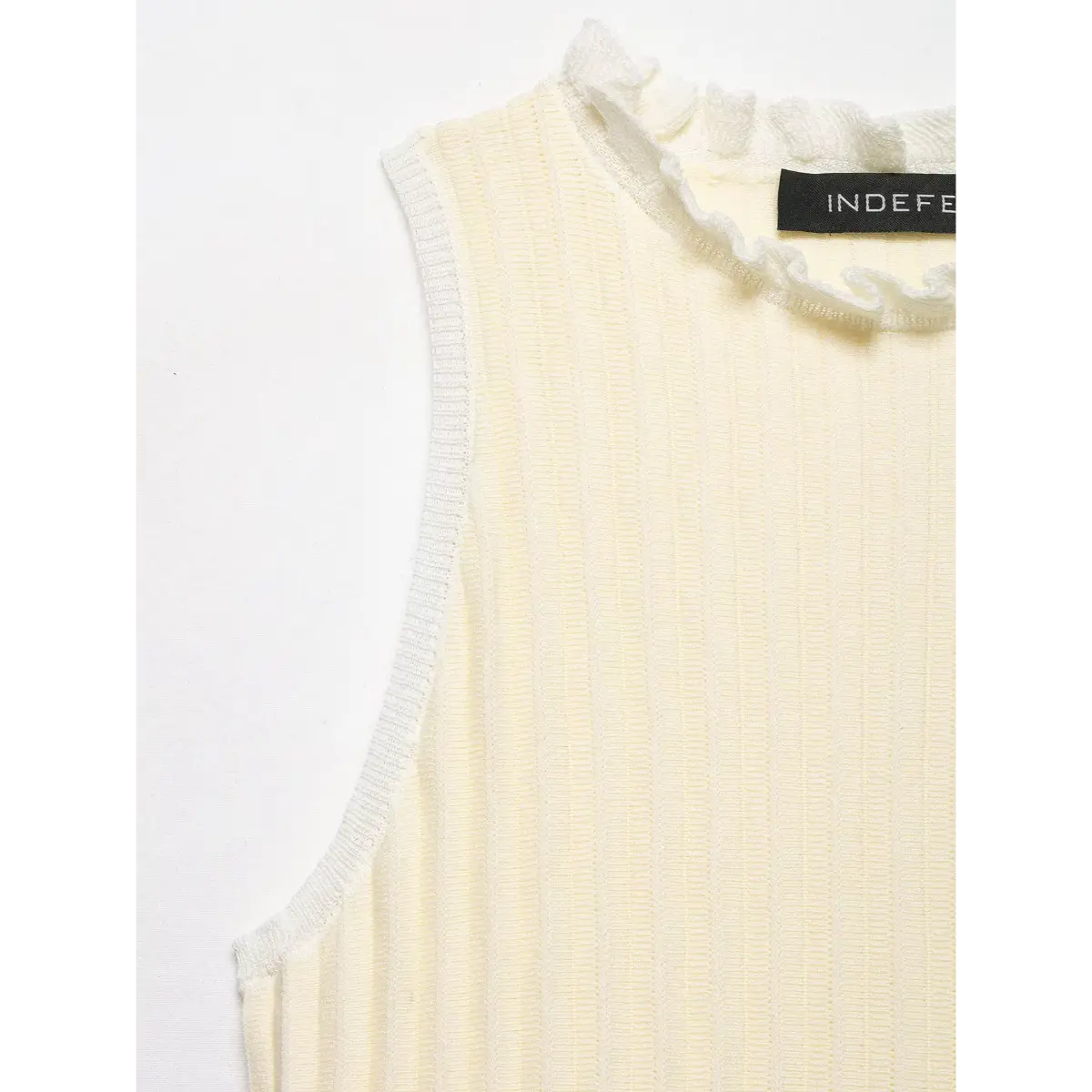 Close-up of the armhole on the cream knit top, showing the clean ribbed binding and vertical texture