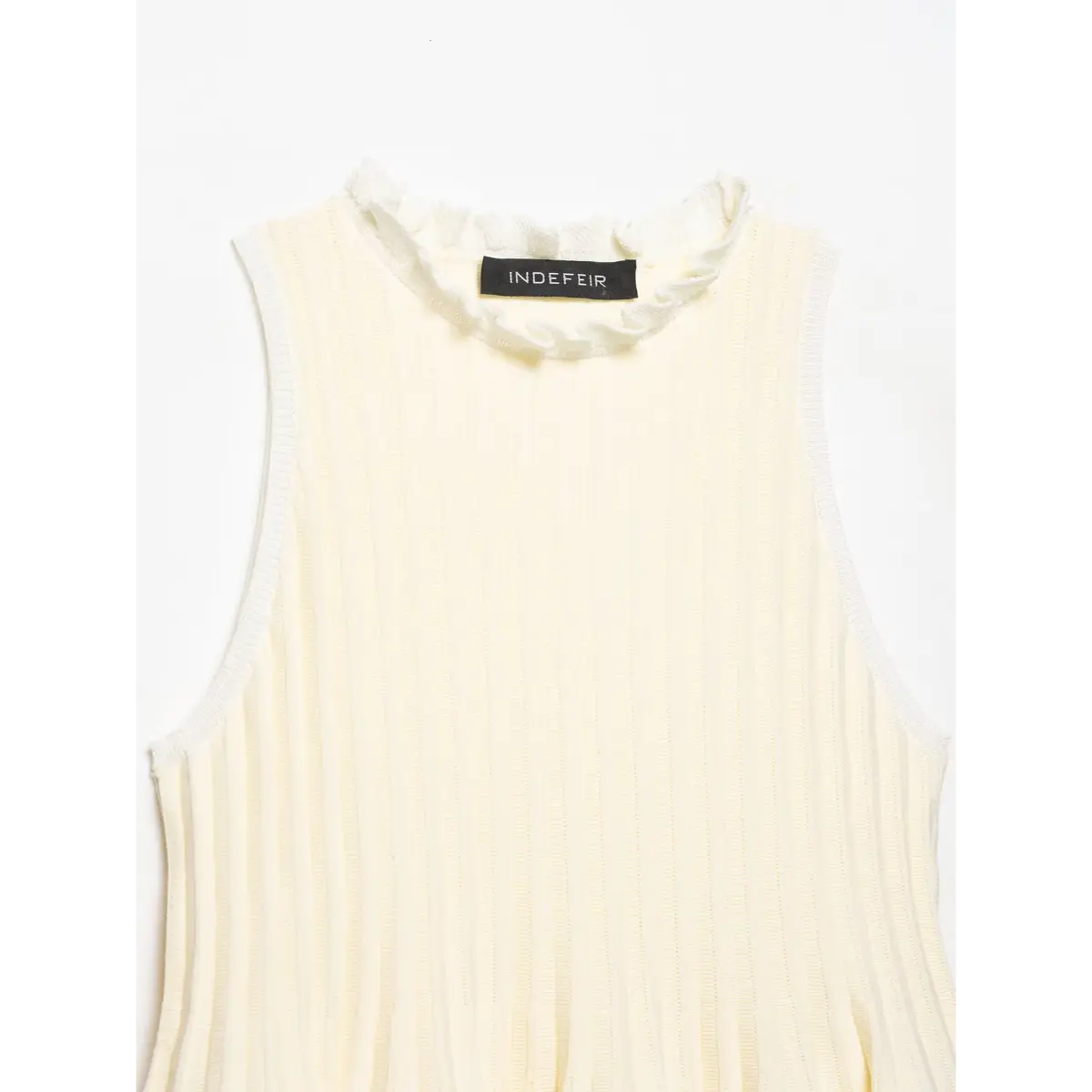 Front view of the cream ribbed knit peplum top, showing the ruffled neckline, sleeveless armholes, and vertical ribbed pattern