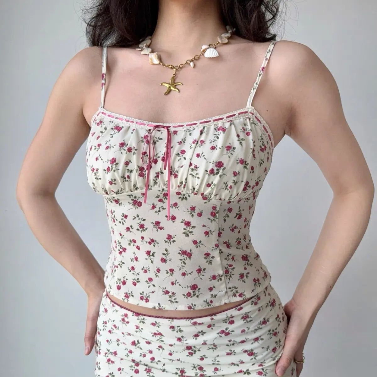 Close-up of the cream camisole top, highlighting the rose print and pink ribbon tie detail.