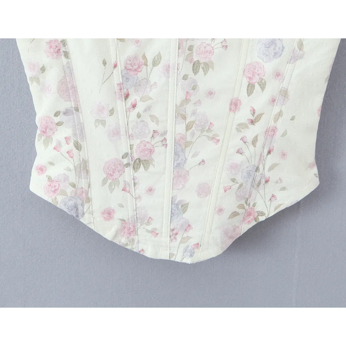 Close-up of scalloped front hem, showcasing floral pattern and corset construction.