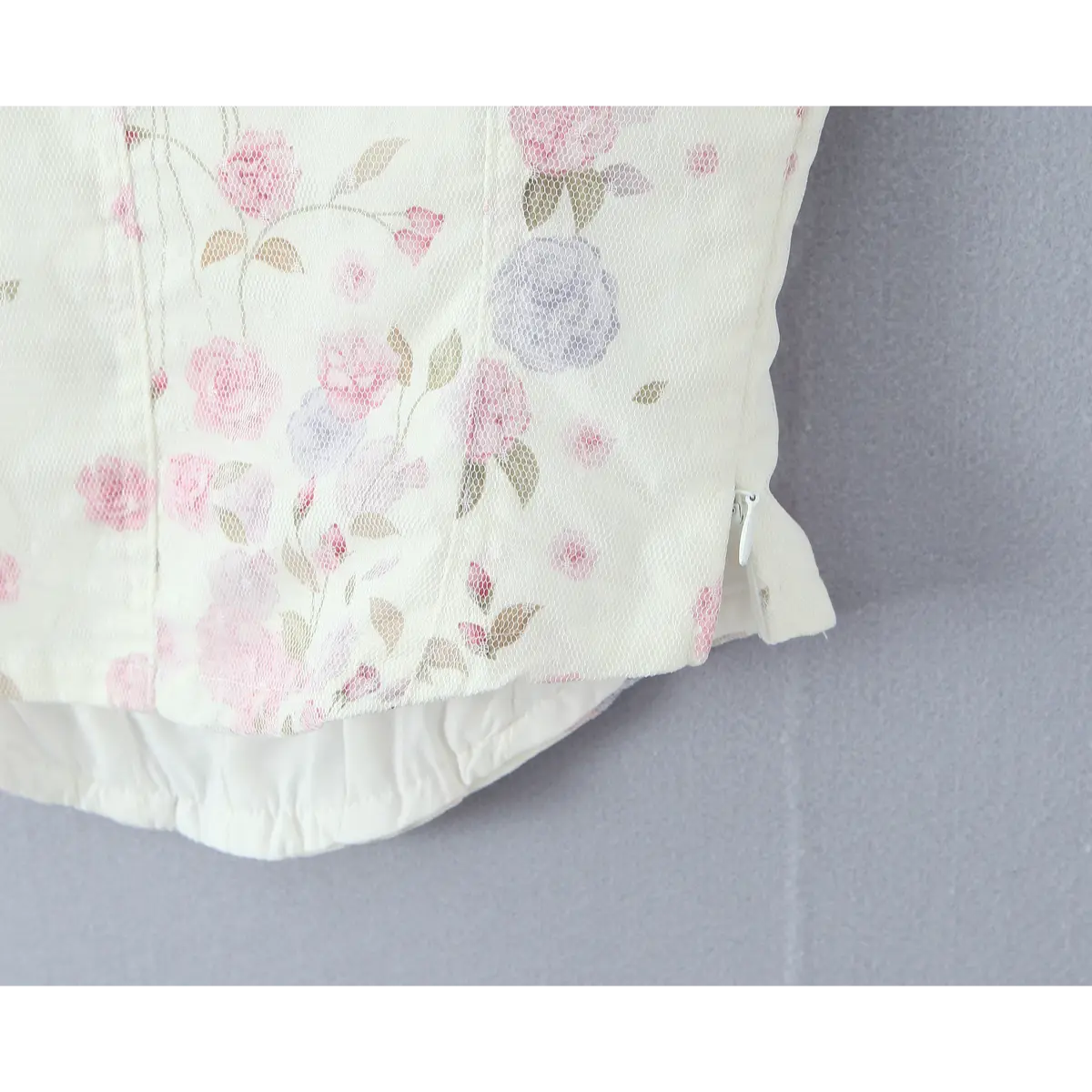 Close-up of corset back showing lining, zipper pull, and layered mesh construction.