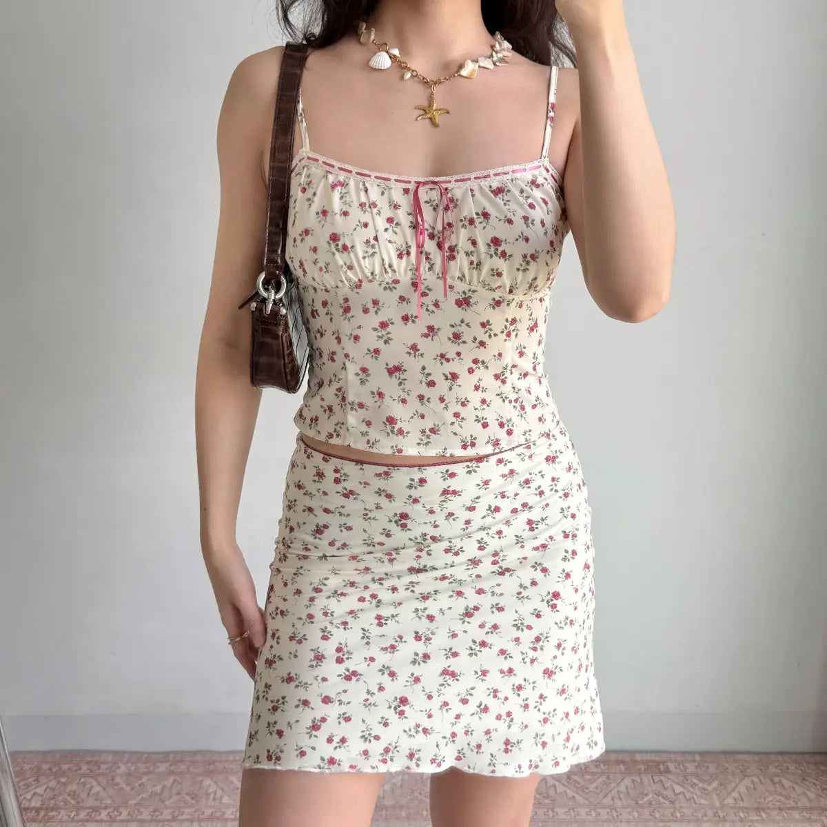 Front view of a cream two-piece set with rose print, camisole top and matching mini skirt.