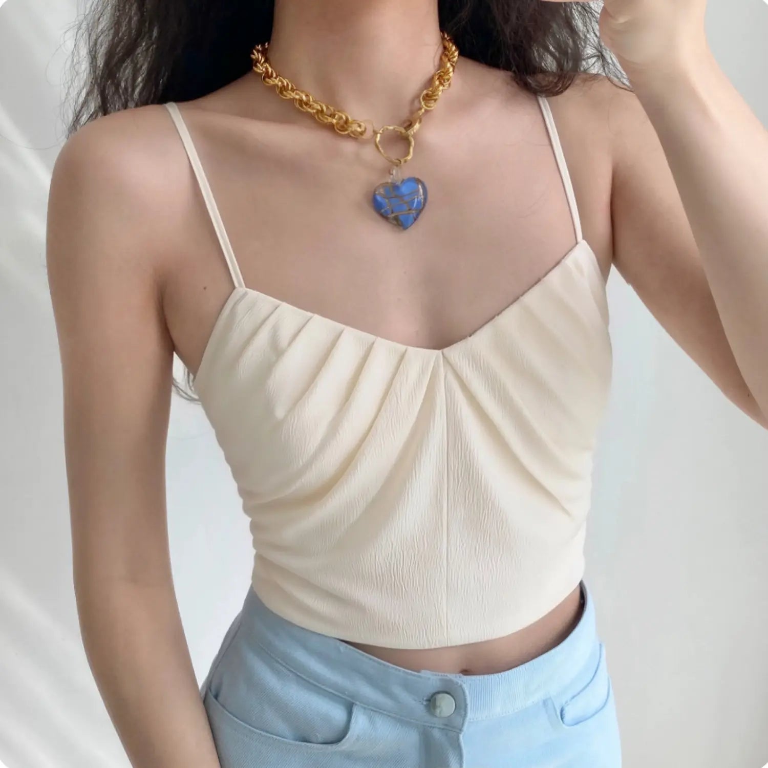 Woman wearing cream ruched v neck crisscross strap camisole crop top casual outfit
