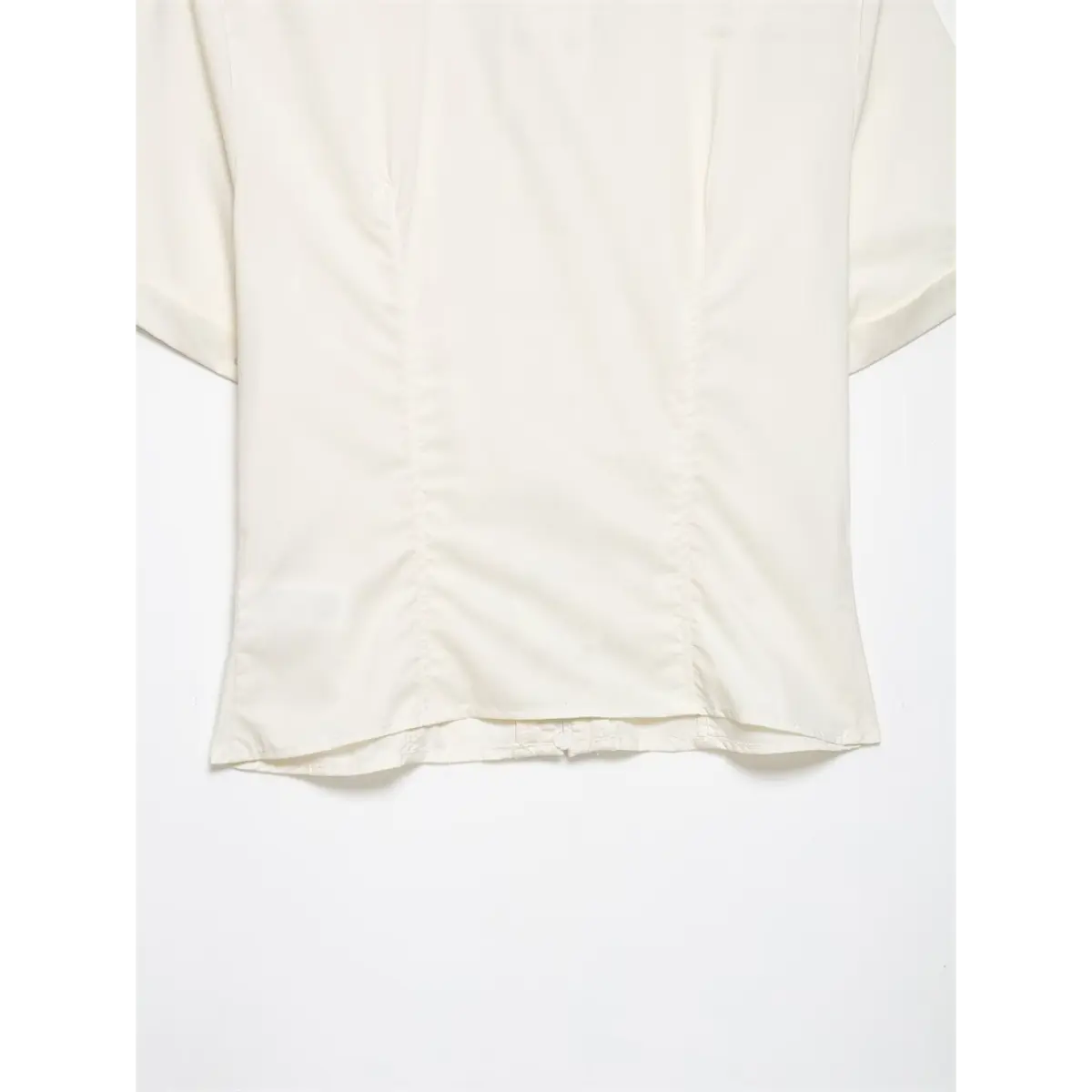 Hem detail of cream ruffle front shirt, showing the finished edge and back closure