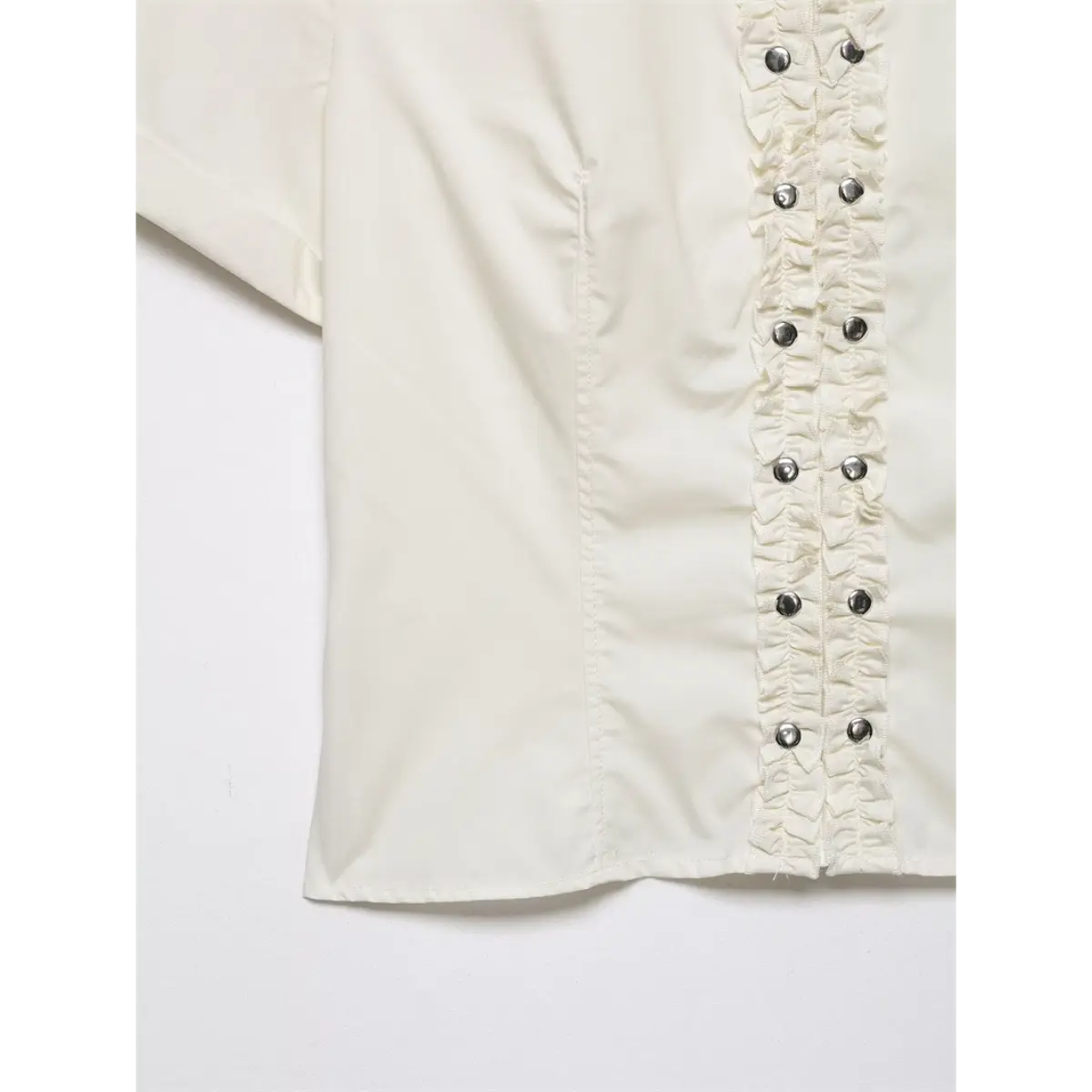 Close-up of the ruffled front placket, showing the metal buttons and gathered fabric