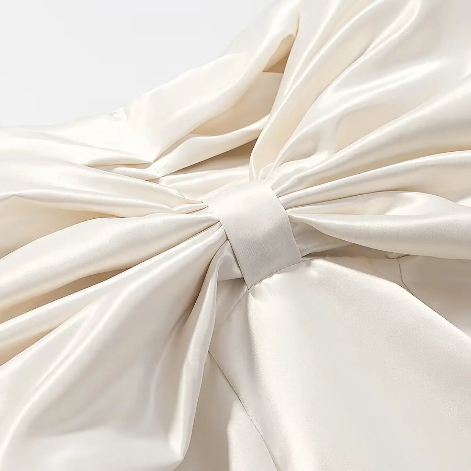 Center knot close-up of oversized satin big bow on cream cropped top
