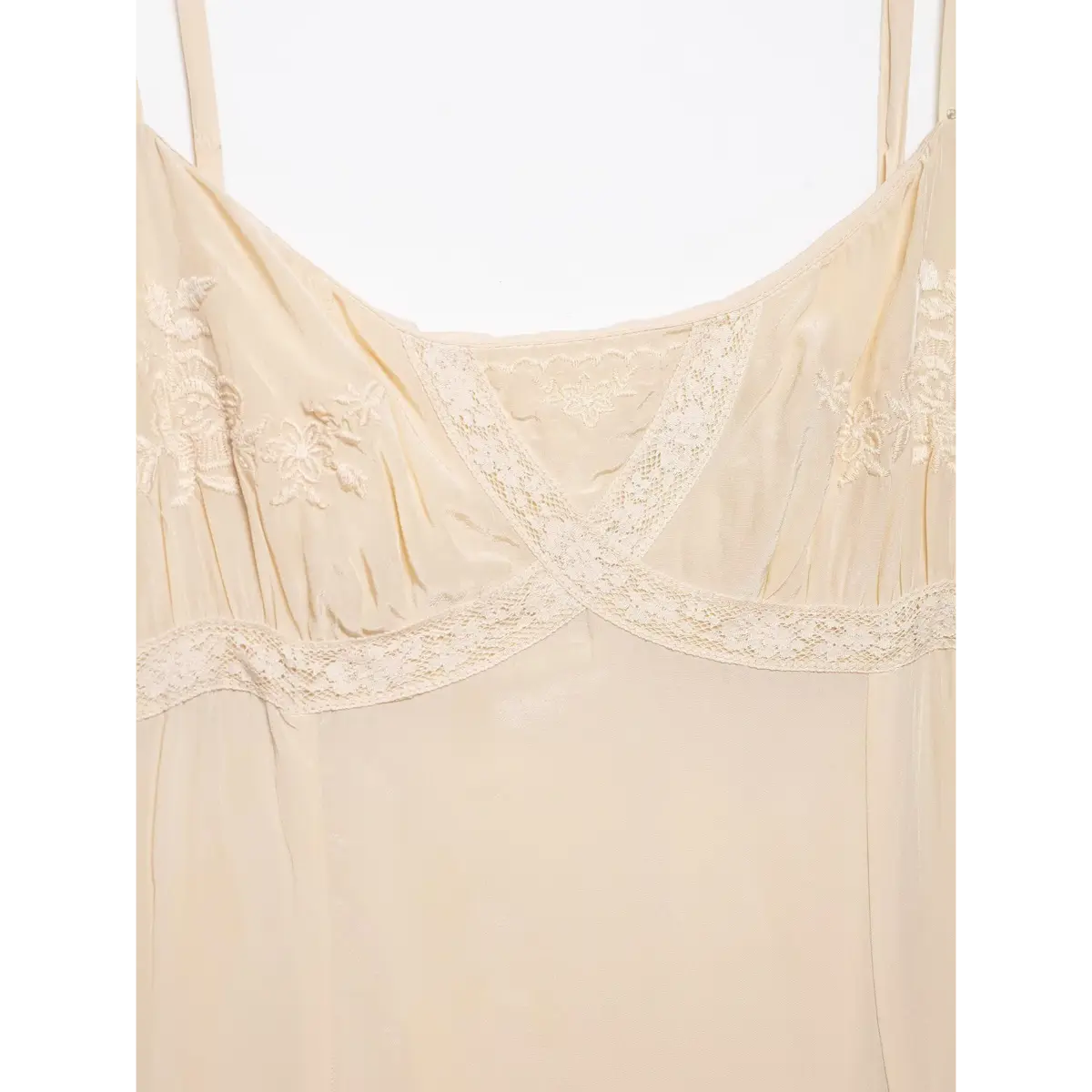 Close-up of the dress's front bodice, showing floral embroidery, crisscross lace trim, and adjustable spaghetti straps.