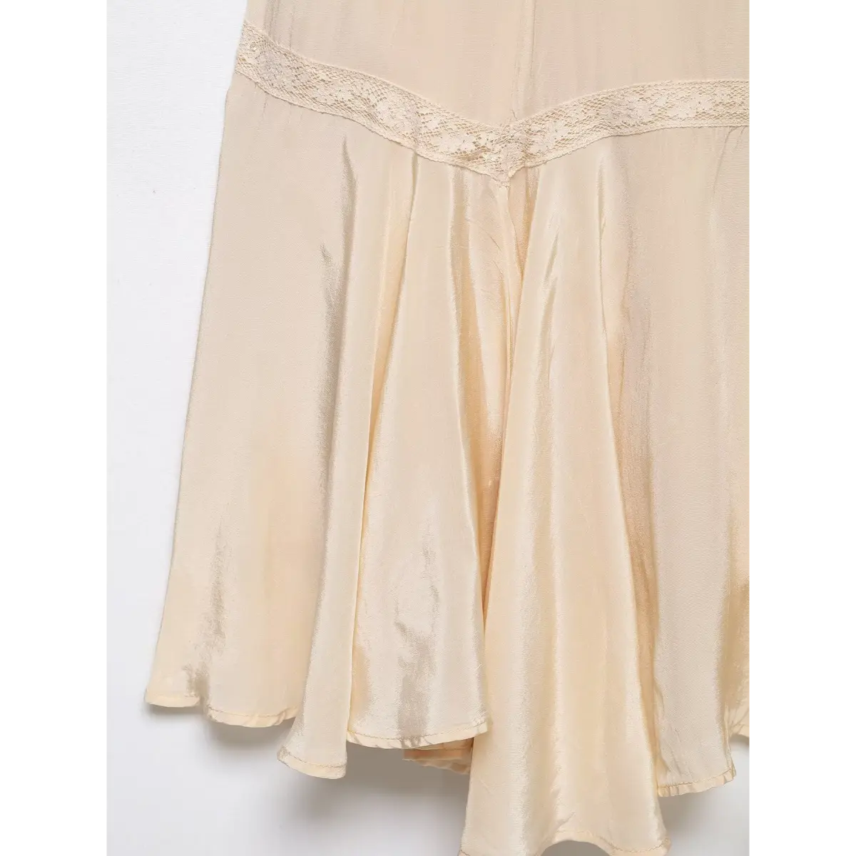 Close-up of the dress's skirt hem, highlighting the scalloped lace trim and satin texture.