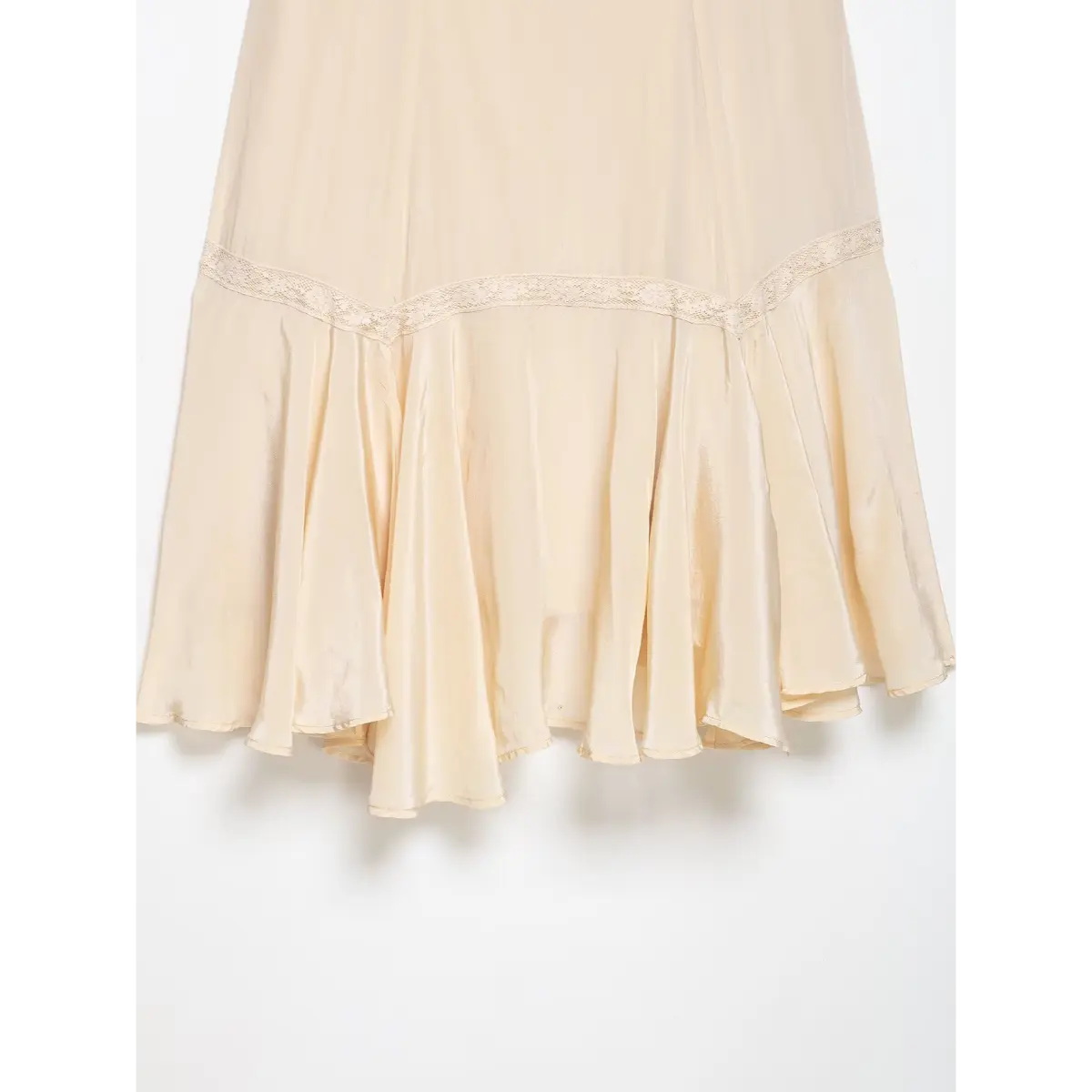 Close-up of the dress's flared skirt hem, featuring a lace-trimmed seam and flowy satin panels.