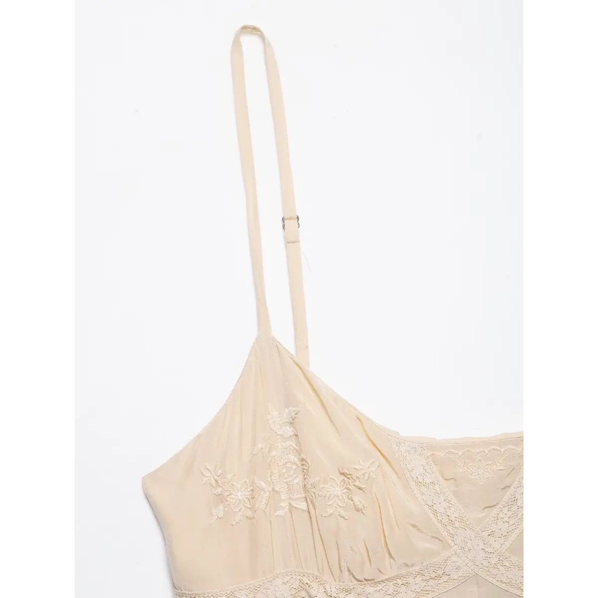 Close-up of the dress's adjustable spaghetti strap, showing the slider buckle and gathered fabric at the bust.