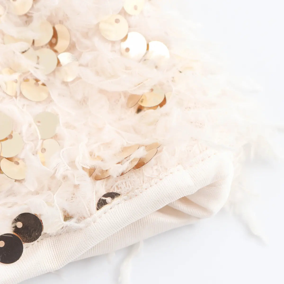 Close-up of the finished hem on the cream feather and sequin bandeau top.