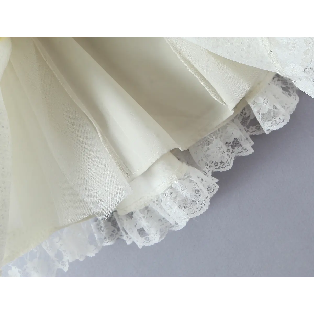 Hem close-up, double-layer skirt with floral lace ruffle trim under outer tweed fabric, full solid inner lining.