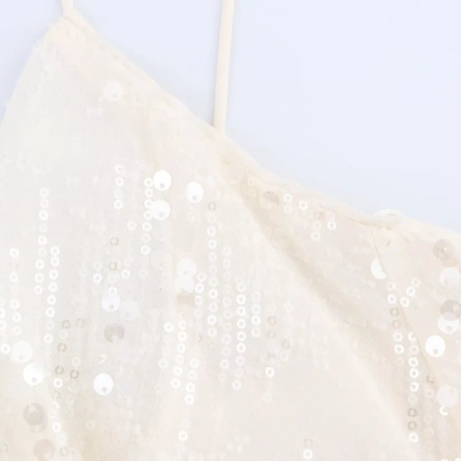 Close-up of the draped cowl neckline and sequin pattern on the cream mesh dress